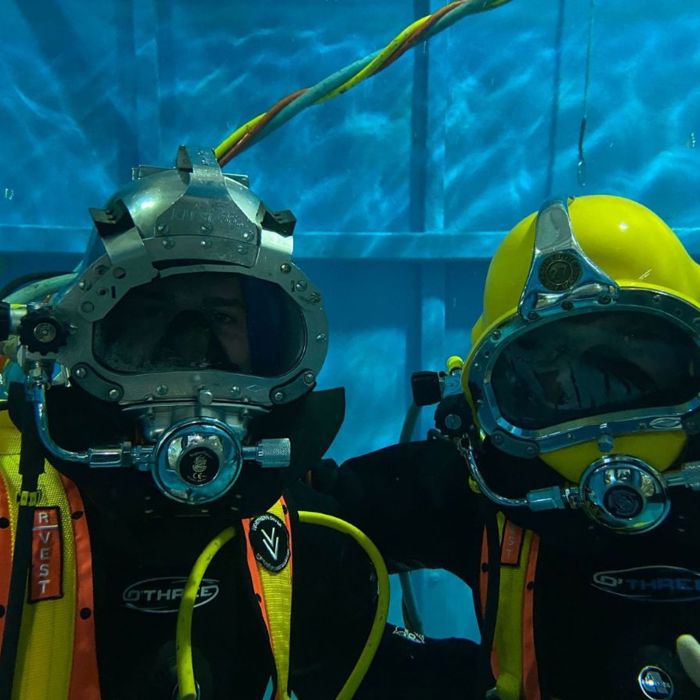 two divers underwater in helmets and breathing apparatus