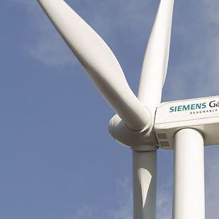 Close-up of a Siemens Gamesa wind turbine with three blades against a clear blue sky.