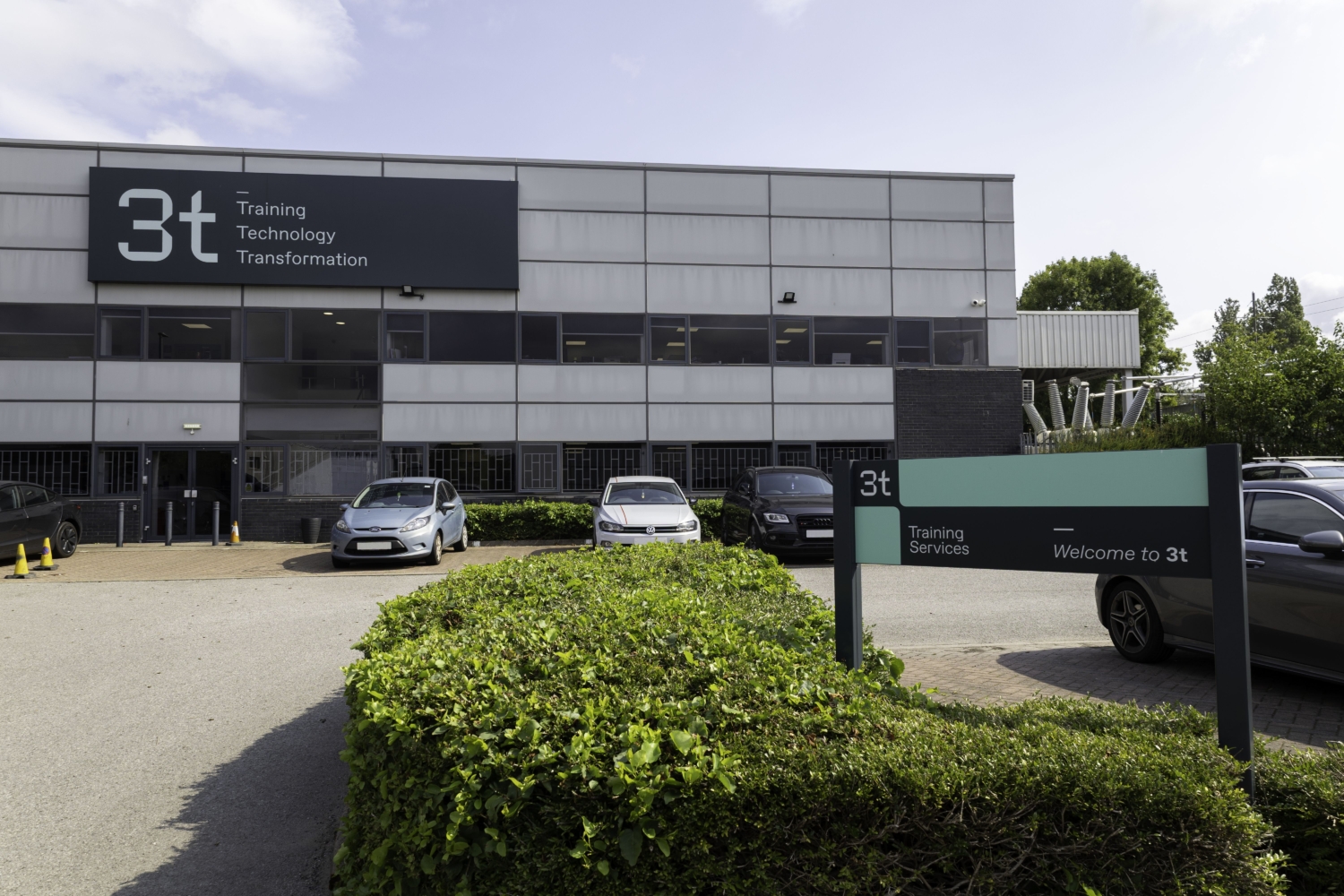 External photo of grey building with car park